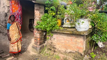 Woman in saree standing outside tiny home.