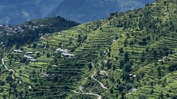 Very steep mountainside with lots of small terraces. and a few buildings.