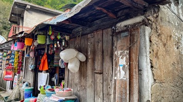 Shop made from wood and mud with  everyday items for sale outside.