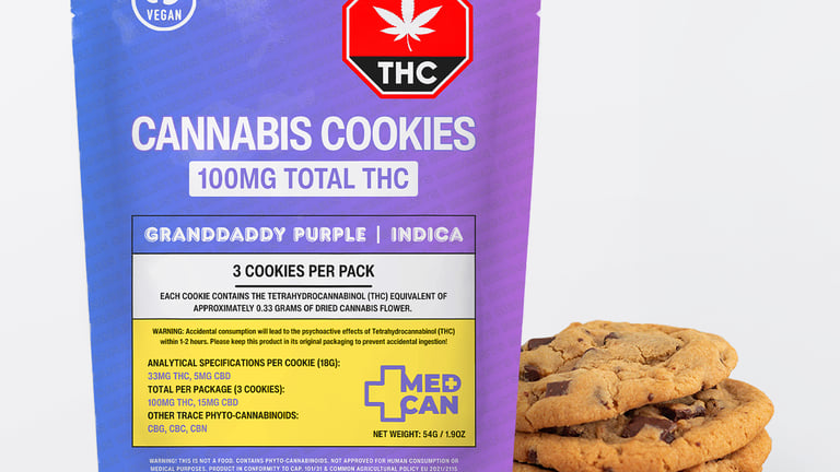 A purple pouch of Granddaddy Purple Indica cannabis cookies next to a stack of chocolate chip edibles.