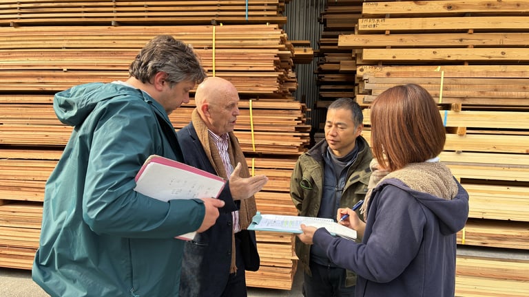 A group of professionals discussing quality control in front of large stacks of industrial lumber boards.