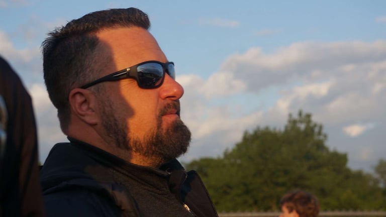 a man with a beard and sunglasses on a sunny day