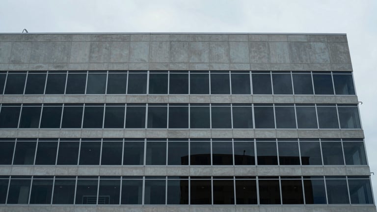 Wide-angle architectural perspective of a modern, minimalist office building facade in downtown Tampa, overcast morning light, muted desaturated blue and concrete tones, sharp focus, 35mm lens