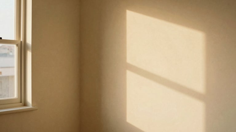 Wide panoramic shot of a quiet, warm creative studio corner at golden hour, soft shadows cast on a creamy beige wall, negative space to the left, 35mm
