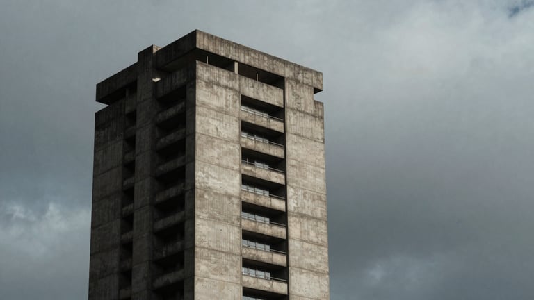 Stark architectural geometry of a concrete brutalist tower rising into an overcast, heavy gray sky, high-contrast side lighting, deep shadows, desaturated moody tones, medium-format film.
