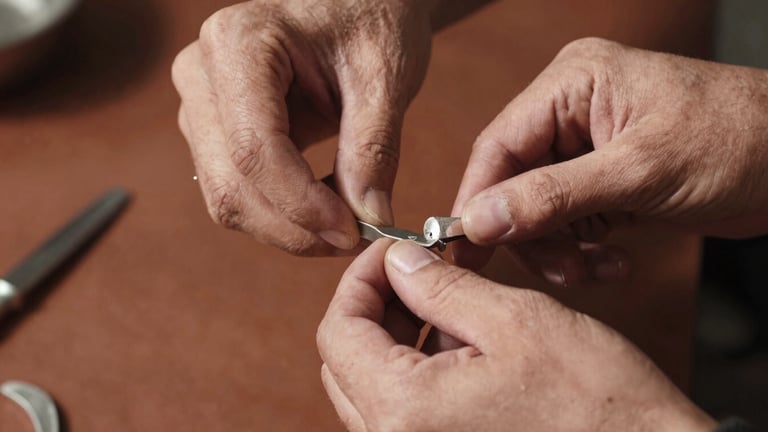 Close-up of artisan hands meticulously working raw silver with traditional tools, harsh natural sunlight, deep shadows, textured metal, warm editorial photography.