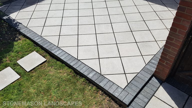 Basic grey patio with black charcoal edging blocks slabs laid in diamond format