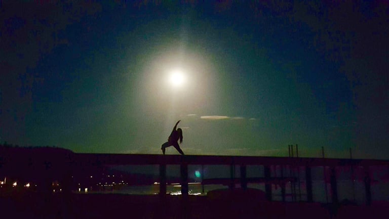 Kiera Goetz under a full moon at Lake Tahoe while the water is low in reverse warroir yoga pose