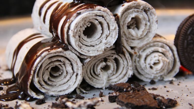 Handmade rolled ice cream with chocolate drizzle and crushed chocolate cookies.