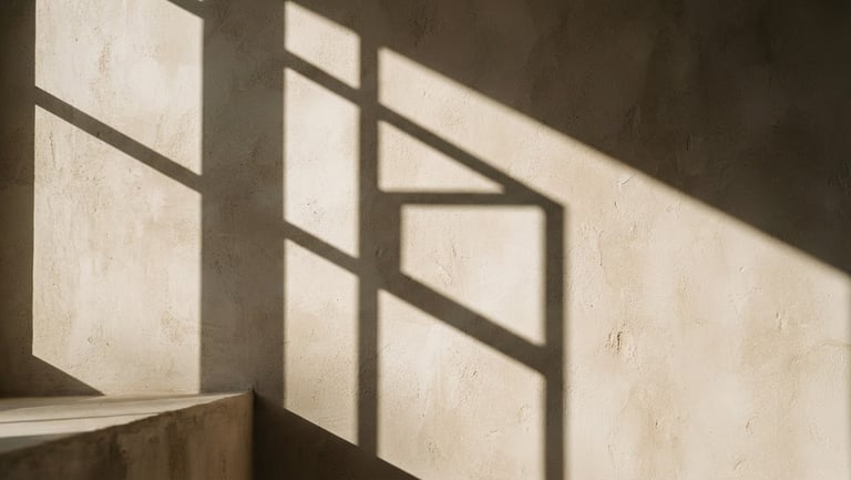 A close-up of natural sunlight casting sharp, architectural shadows on a warm, textured ivory stone wall, minimalist and calm