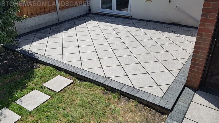 Basic grey patio with black charcoal edging blocks slabs laid in diamond format