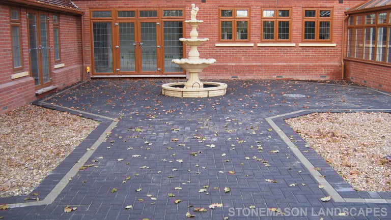 Charcoal standard block paving large patio and glass wall.