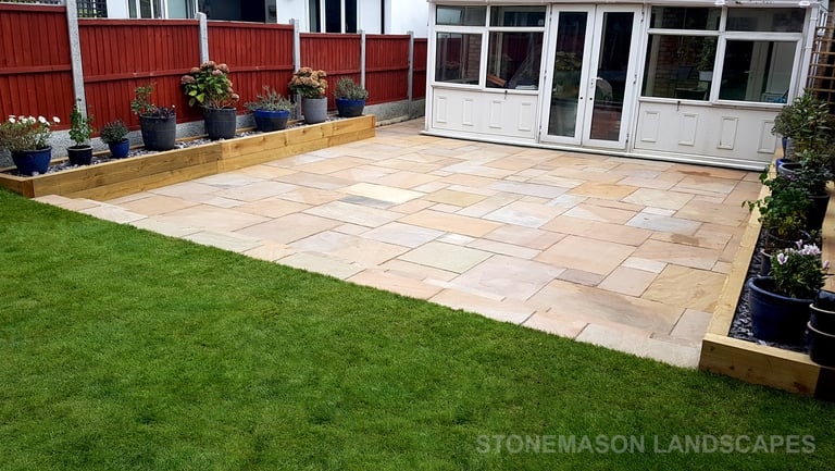 Large sandstone patio and raised wooden sleeper planters