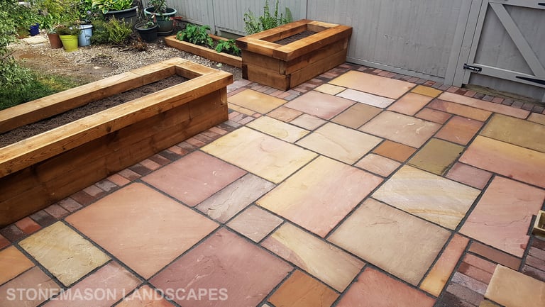 Colourful sandstone patio with raised wooden timber planter seating