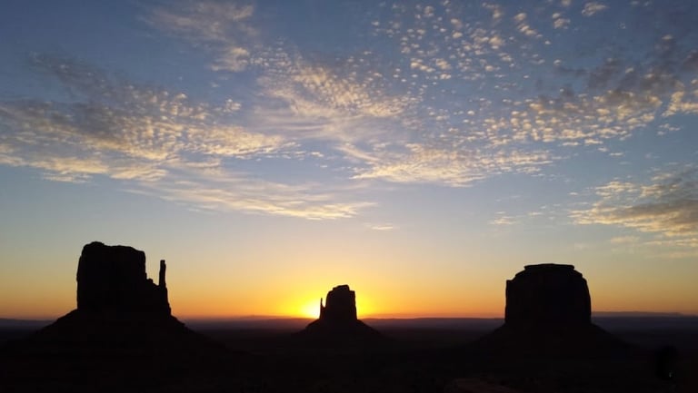 Monument Valley sunrise silhouettes West Mitten Butte, East Mitten Butte, and Merrick Butte