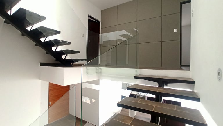 escalera panorámica que conecta los 3 niveles con barandal en cristal