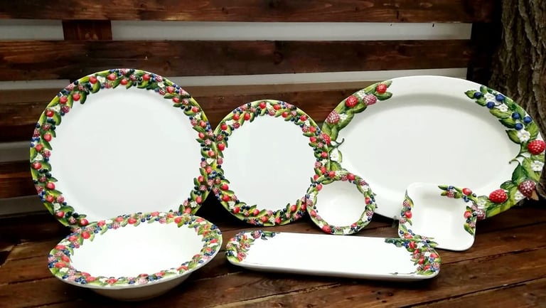 Hand-painted ceramic dinnerware set featuring 3D fruit borders with berries and leaves on a rustic wood background.