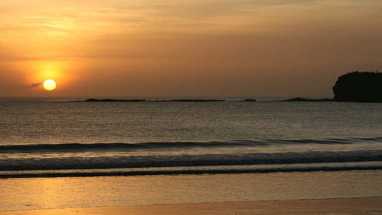 Golden hour sunset over the Pacific Ocean in San Juan del Sur, Nicaragua, featuring a tranquil beach