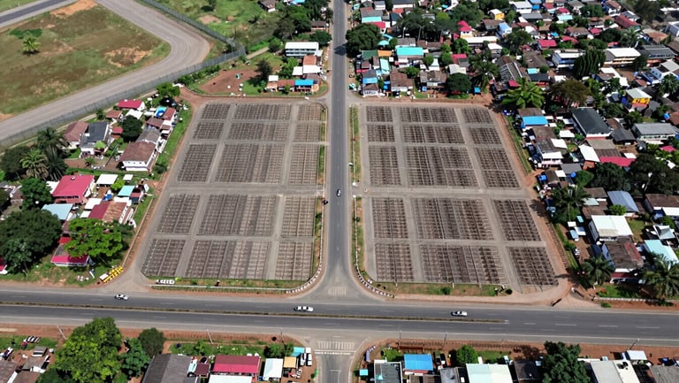Overhead drone photograph in bright neutral daylight showing the Sulur township road grid, demarcated plot boundaries clearly visible, Coimbatore airport perimeter fencing in the upper-left corner, NH-544 highway running horizontally across the lower third, scale giving clear sense of proximity