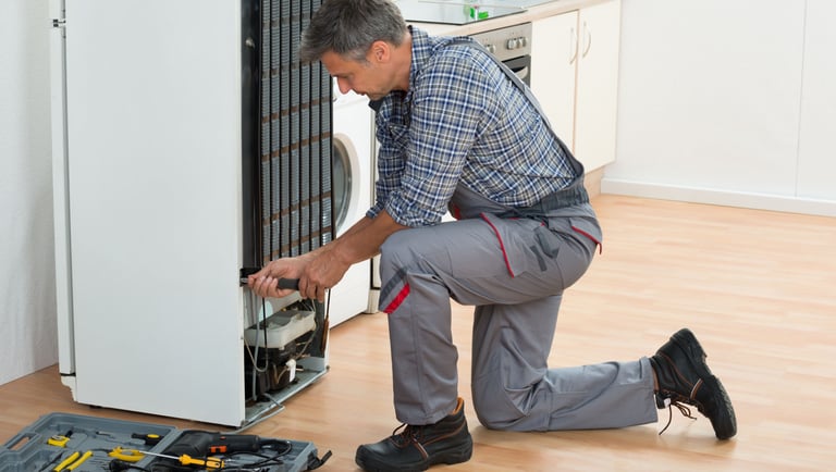 a man in a plaid shirt and pants is fixing a dishwasher