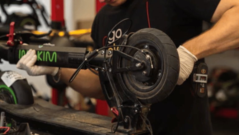 a man in a black shirt and a red hat with a red cap fixing an escooter