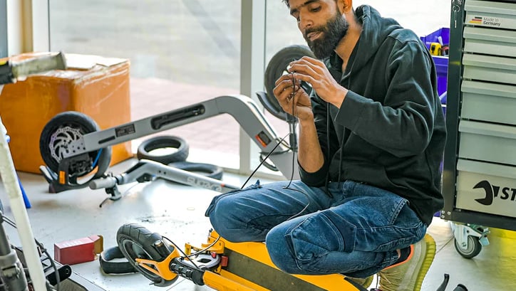 a man fixing an escooter in a garage