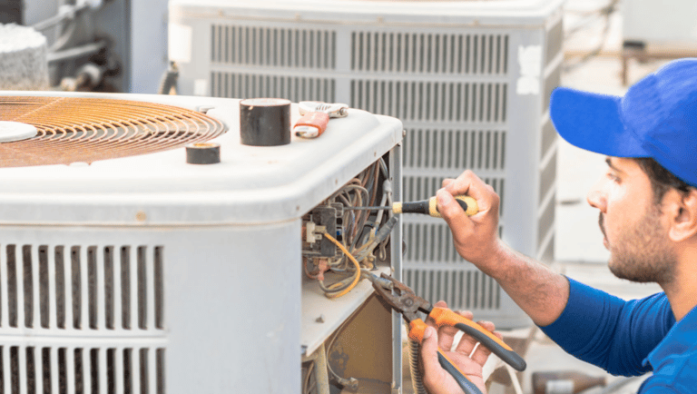 a man in a blue shirt is working on a large air conditioner