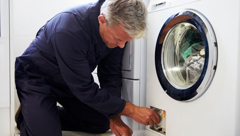 a man in a blue suit is cleaning a washing machine