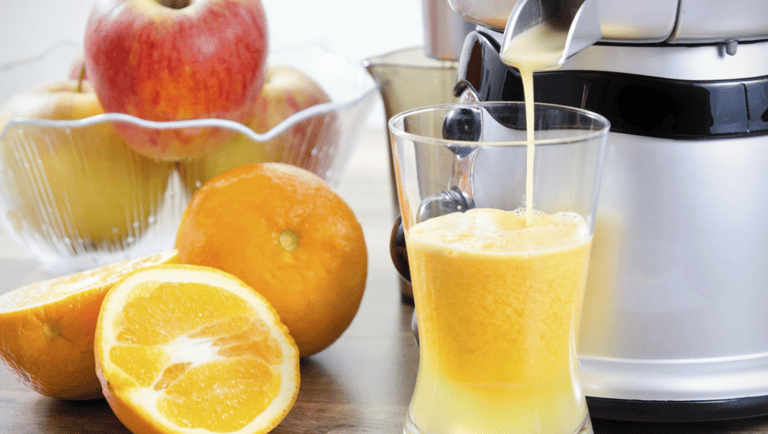 a juicer with orange juice being poured into a glass