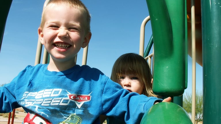 Boy sliding for sensory input on play structure during OT session