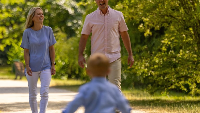 Familienshooting Coburg: Fröhlicher Sohn rennt lachend auf seine Eltern zu, pure Lebensfreude.
