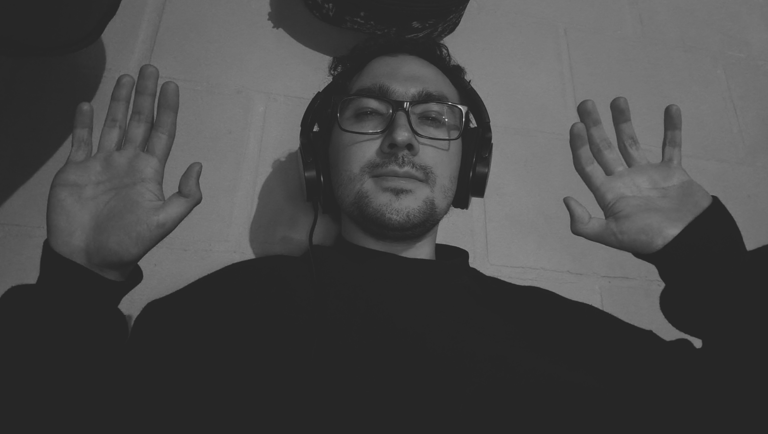 Imagen en blanco y negro de hombre con audífonos y manos levantadas.
