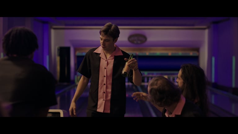 a man in a bowling shirt is holding a bottle of beer