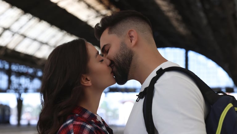 Una pareja dándose un beso al despedirse en una estación de tren porque viven lejos el uno del otro.
