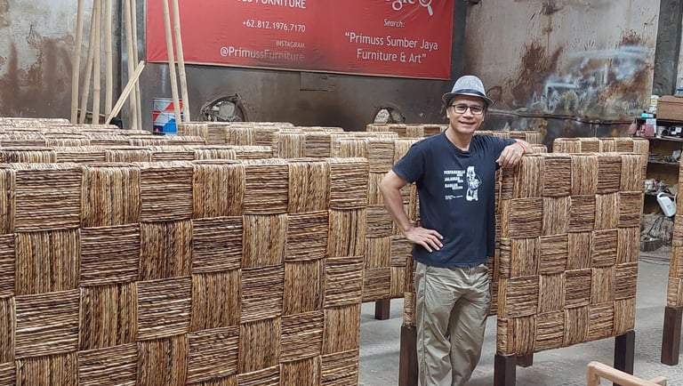 Jiwo standing in front of a large group of headboard weaved by banana fiber