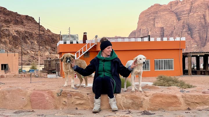 a woman in a green coat and dogs on a rock formation
