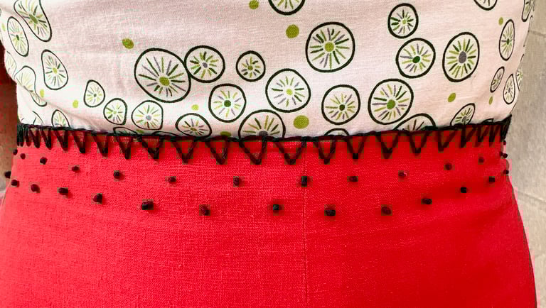 Embroidered waist of a white, green, and red strappy sundress
