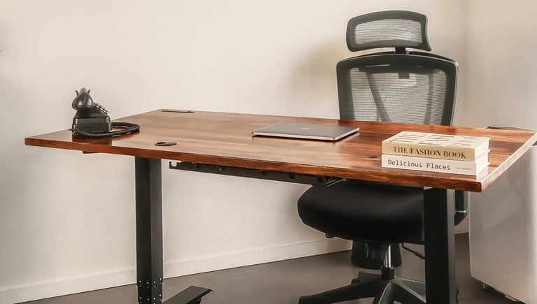 A chair behind a desk with a closed laptop, books, and old-style phone.
