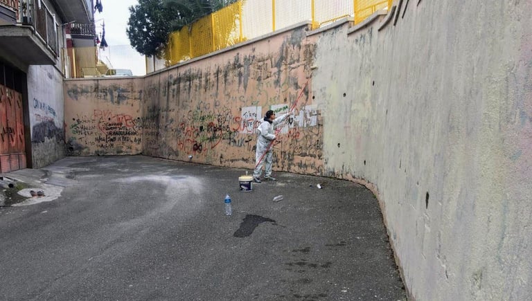 Preparing the wall for an urban mural, Poliops applies a white base coat before decorative painting.