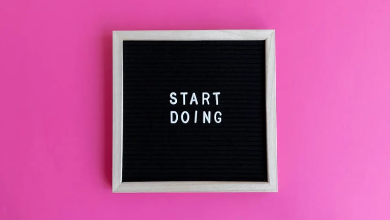 Inspirational black letter board with Start Doing message on a vibrant pink background.