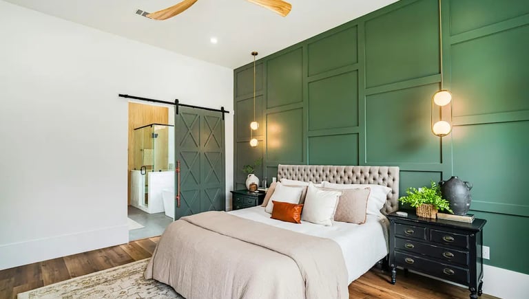 Modern bedroom with dark green board and batten accent wall, tufted headboard, and sliding barn door.