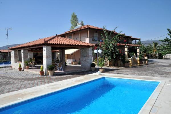 Luxurious villa with a clear blue swimming pool and a shaded outdoor seating area, perfect for a relaxing vacation.