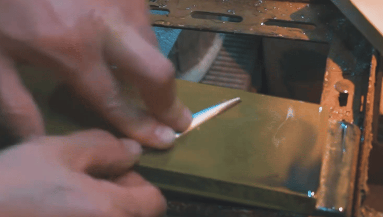 Una persona afilando a mano unas tijeras en una piedra profesional para obtener un filo extremadamen