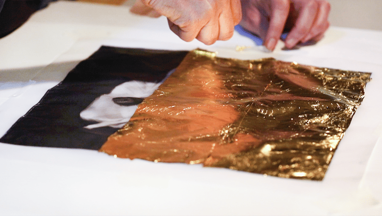 a person who applies 24-carat gold leaf on a photographic print