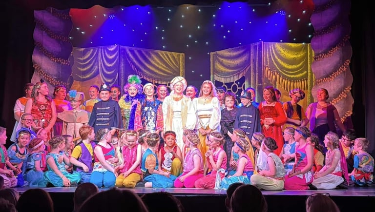 Group photo of the cast of Aladdin on stage at Theatr Colwyn