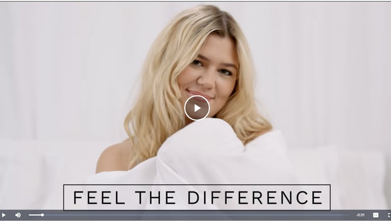 Blonde woman smiling in white bedding with Feel the Difference text overlay.
