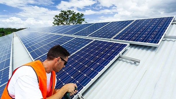 Professional technician installing solar panels on a residential rooftop for renewable energy.