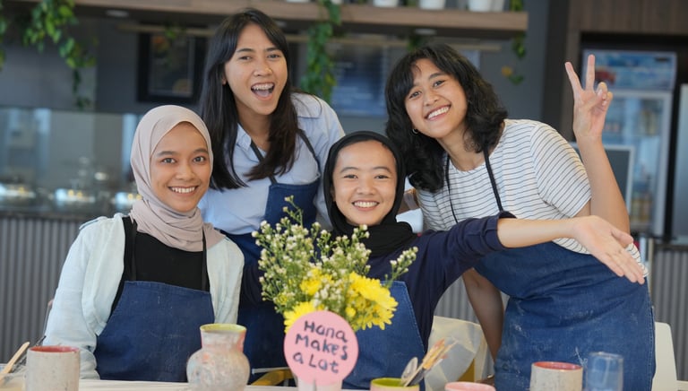 a group of women posing behind a table with flowers and handmade pots