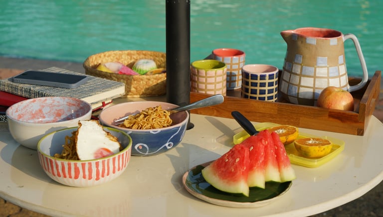 a table by the pool with a tray of food served on colorful tableware