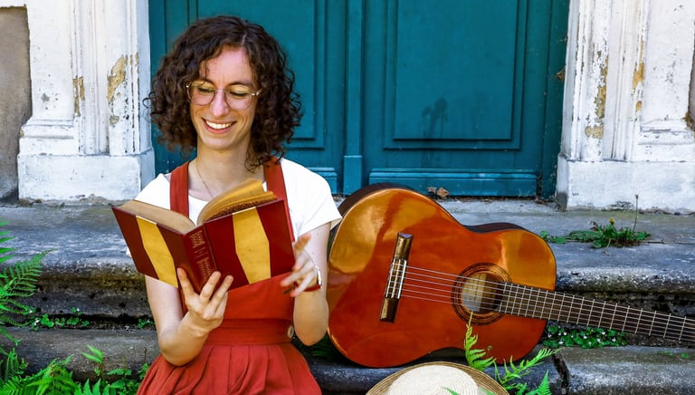 musicienne en train de lire un livre/a woman in a red dress reading on stairs with guitar beside her